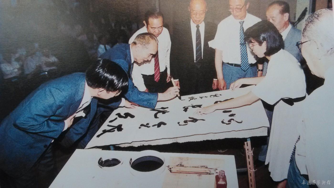 1987年，梁披云（左二）参加“第一届新加坡书法营”开幕，并在现场挥毫示范。潘受在旁观看（背向镜头） 副本