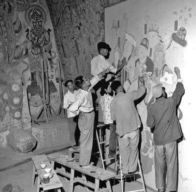 1959年10月,画家常书鸿(左二)在指导敦煌文物研究所工作人员临摹壁画。郝常耕摄
